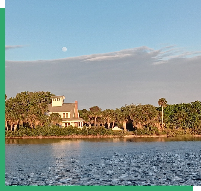 A house on the water with trees in front of it